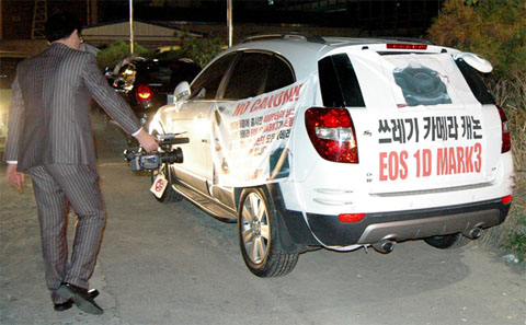 A car belonging to a frustrated Korean photographer. The text on those banners translates to: “Camera that is a piece of trash – Canon EOS 1D Mark 3”